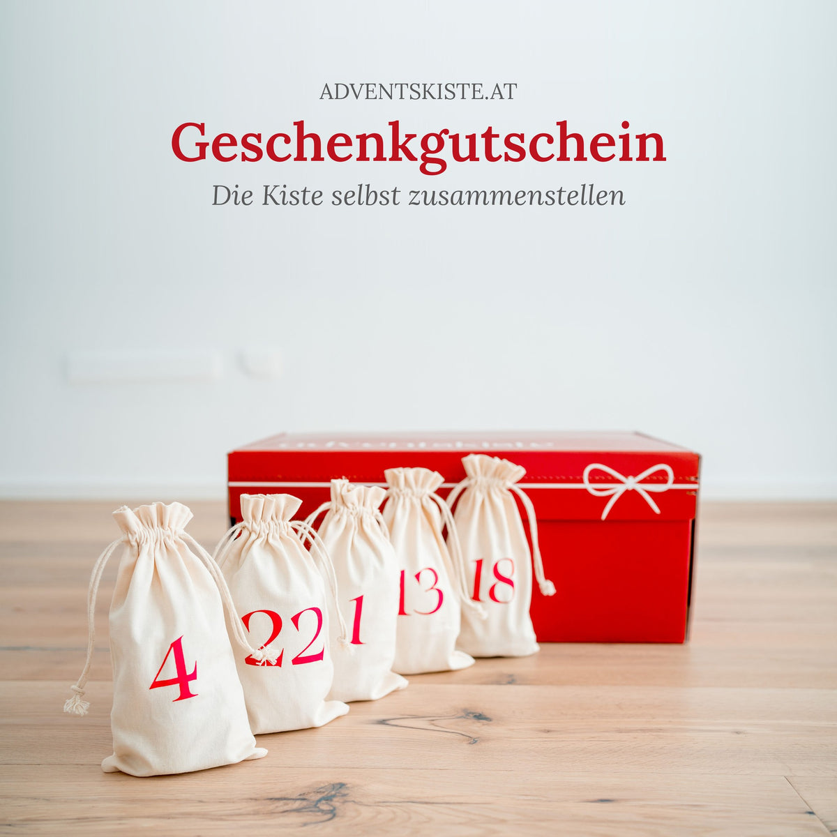 Adventskisten-Gutschein: rote Adventskiste mit Masche und nummerierten Stoffsäckchen