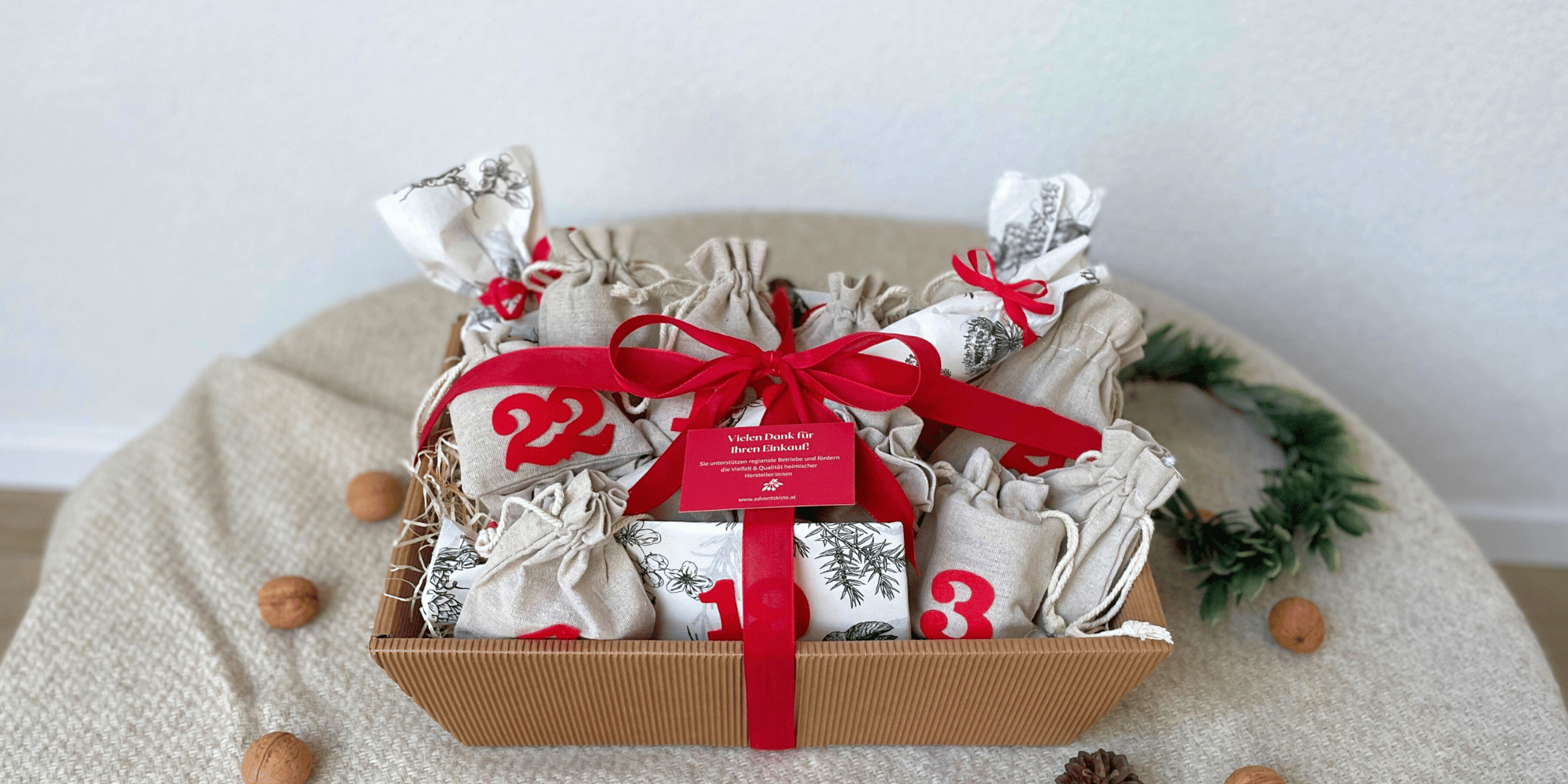 Adventskalender verpackt mit roter Schleife auf Tischtuch